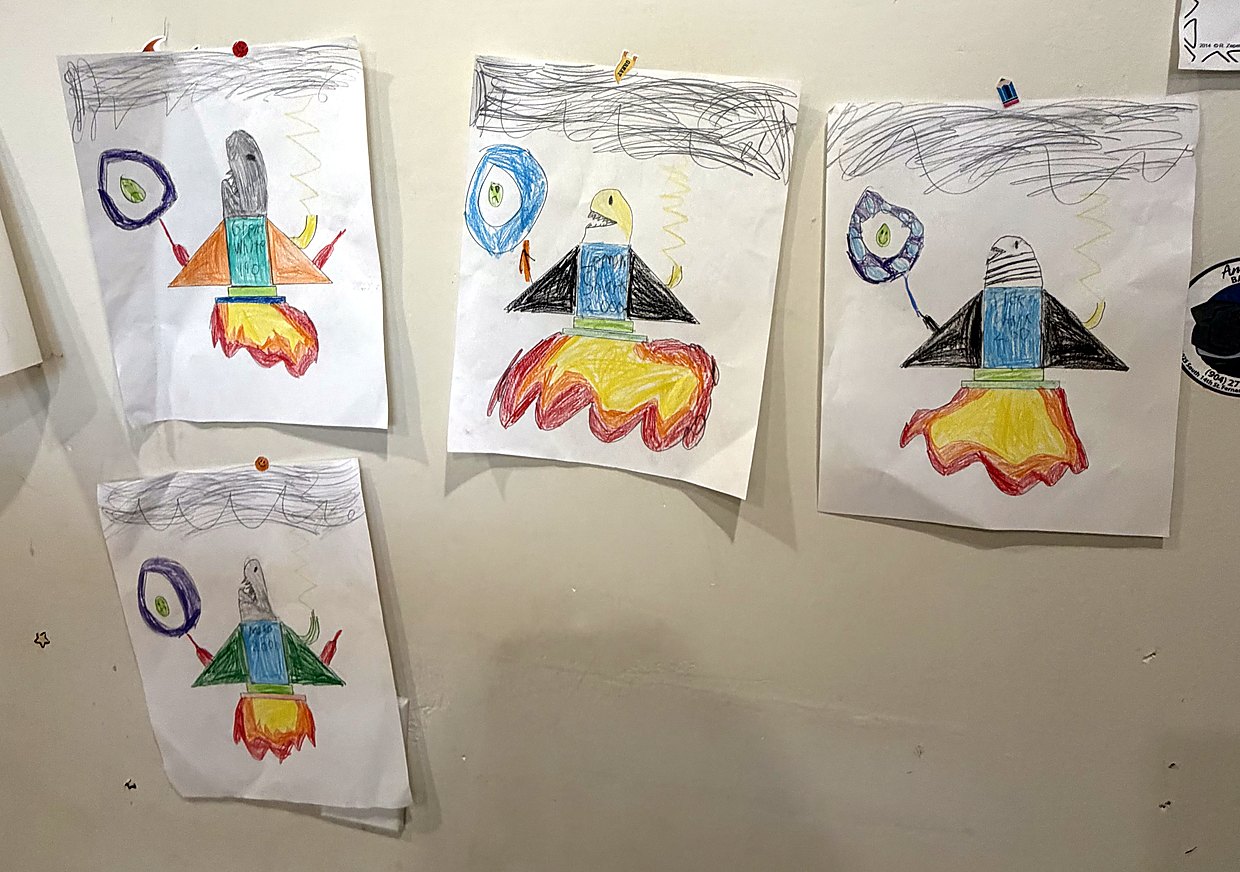 Photo: four crayon rocket sharks pinned in a row on a bedroom wall